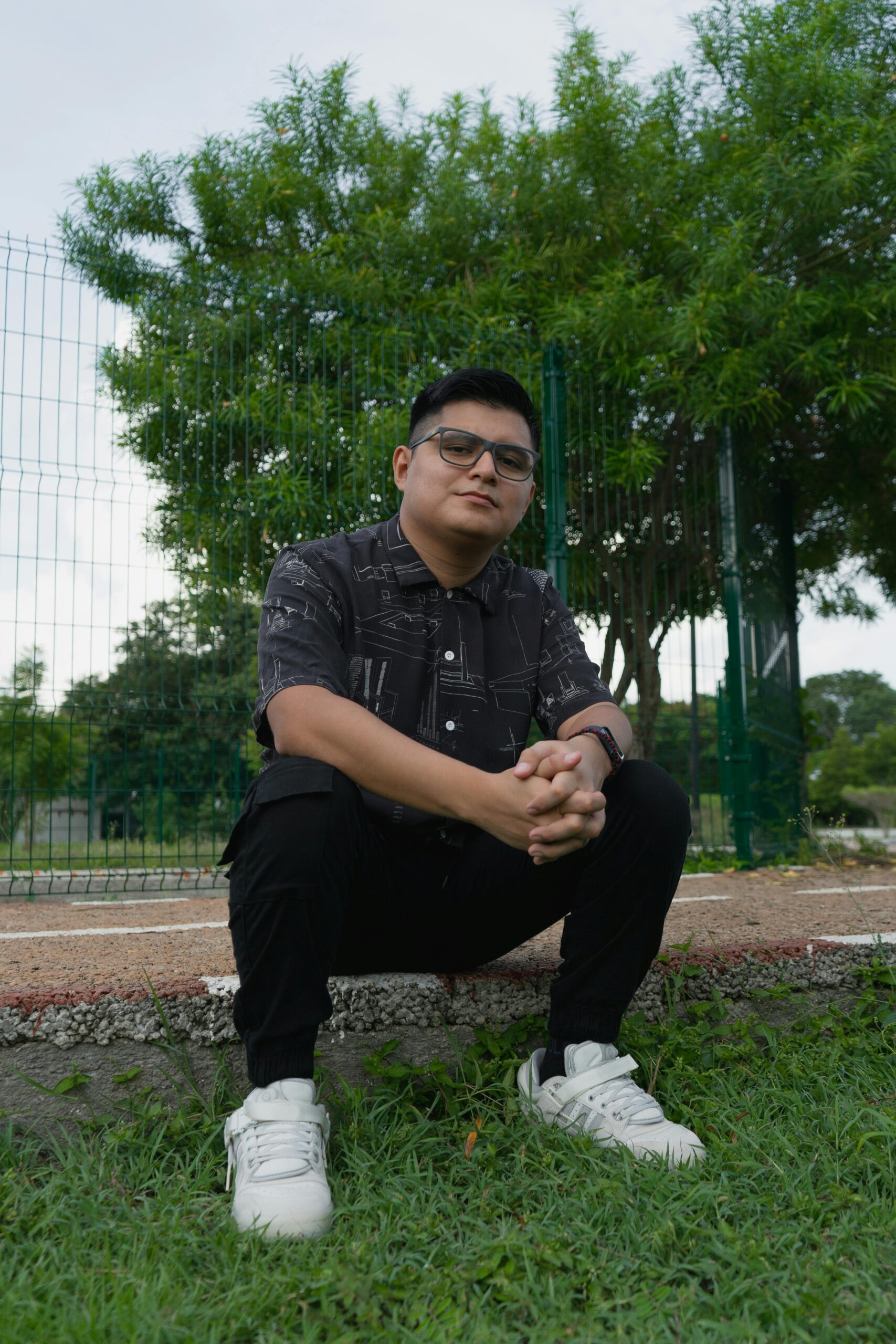 Casual portrait of a man wearing glasses and a watch, seated in a park in Merida, Mexico.